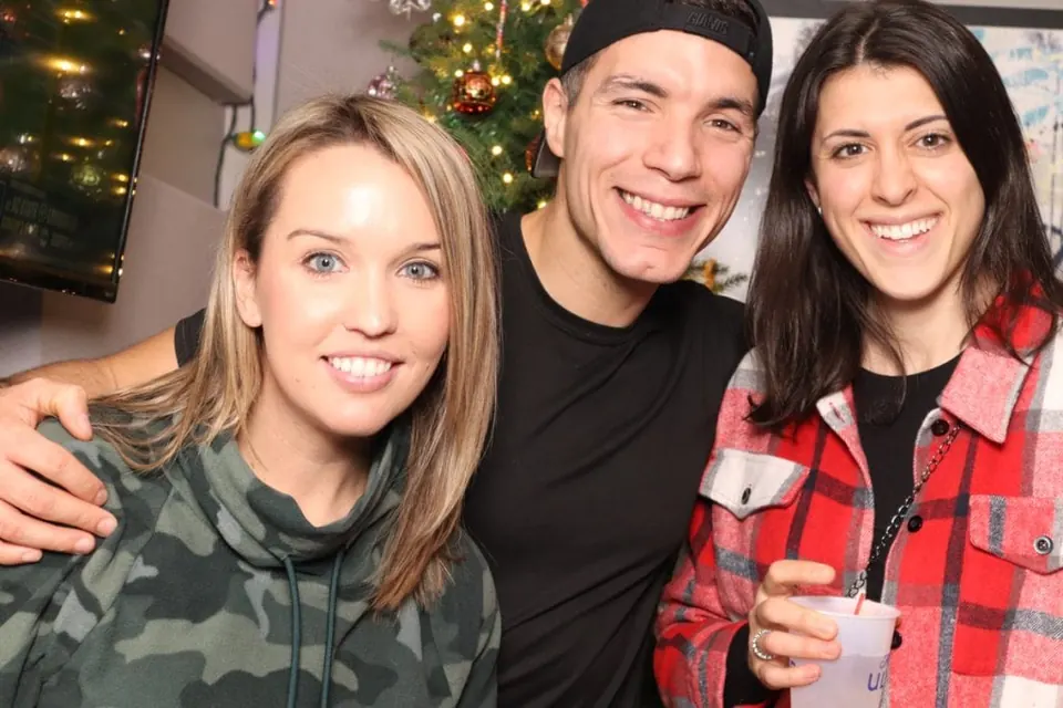 Three friends smiling together at a past bar crawl