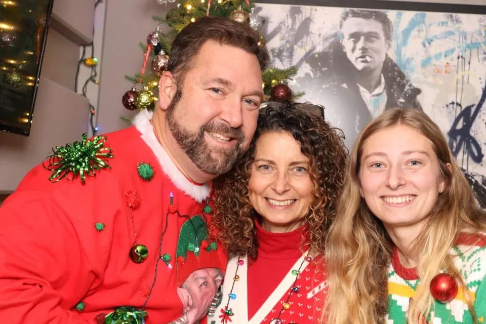 A group in bright handmade ugly Christmas sweaters